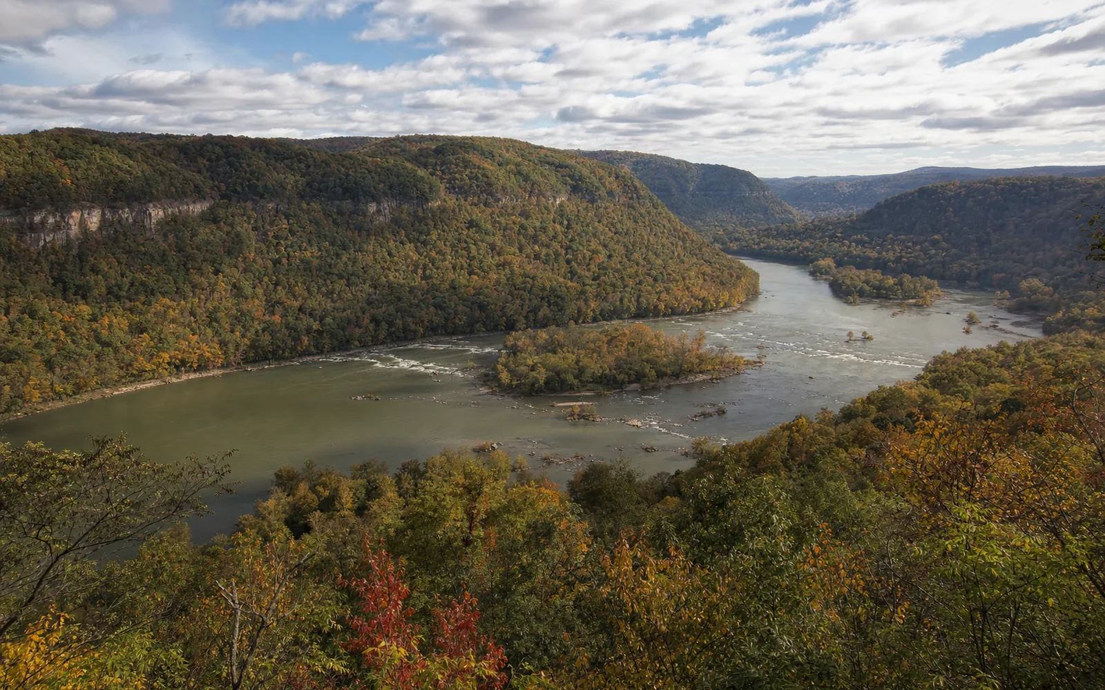 The view from the Sandstone Falls Overlook high on the ridge, the New River far below spreading wide around wooded islands, the pale line of the falls across the river, AI-generated illustration