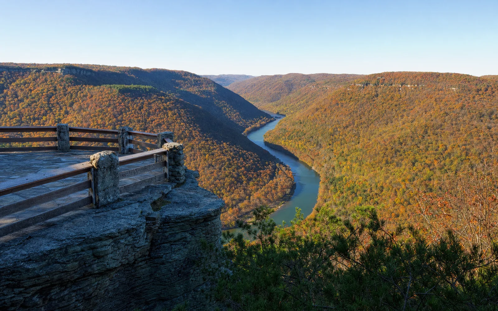 The stone-walled Grandview Main Overlook above a wide horseshoe bend of the New River, with forested ridges fading into haze, AI-generated illustration