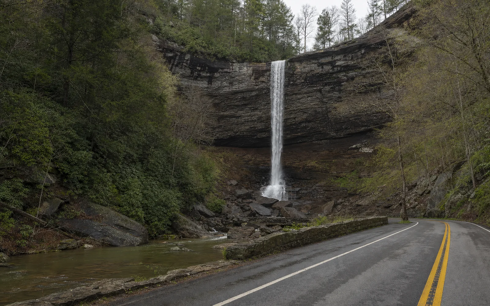 Cathedral Falls, a tall thin waterfall dropping over a dark amphitheater of rock beside a two-lane road, with hemlocks, AI-generated illustration