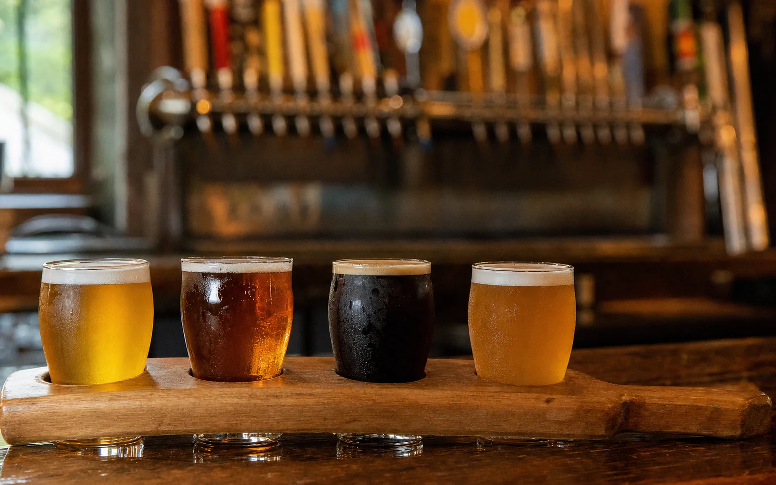 A flight of four beers from pale gold to near black on a wooden paddle, with a long row of tap handles blurred behind the bar, AI-generated illustration