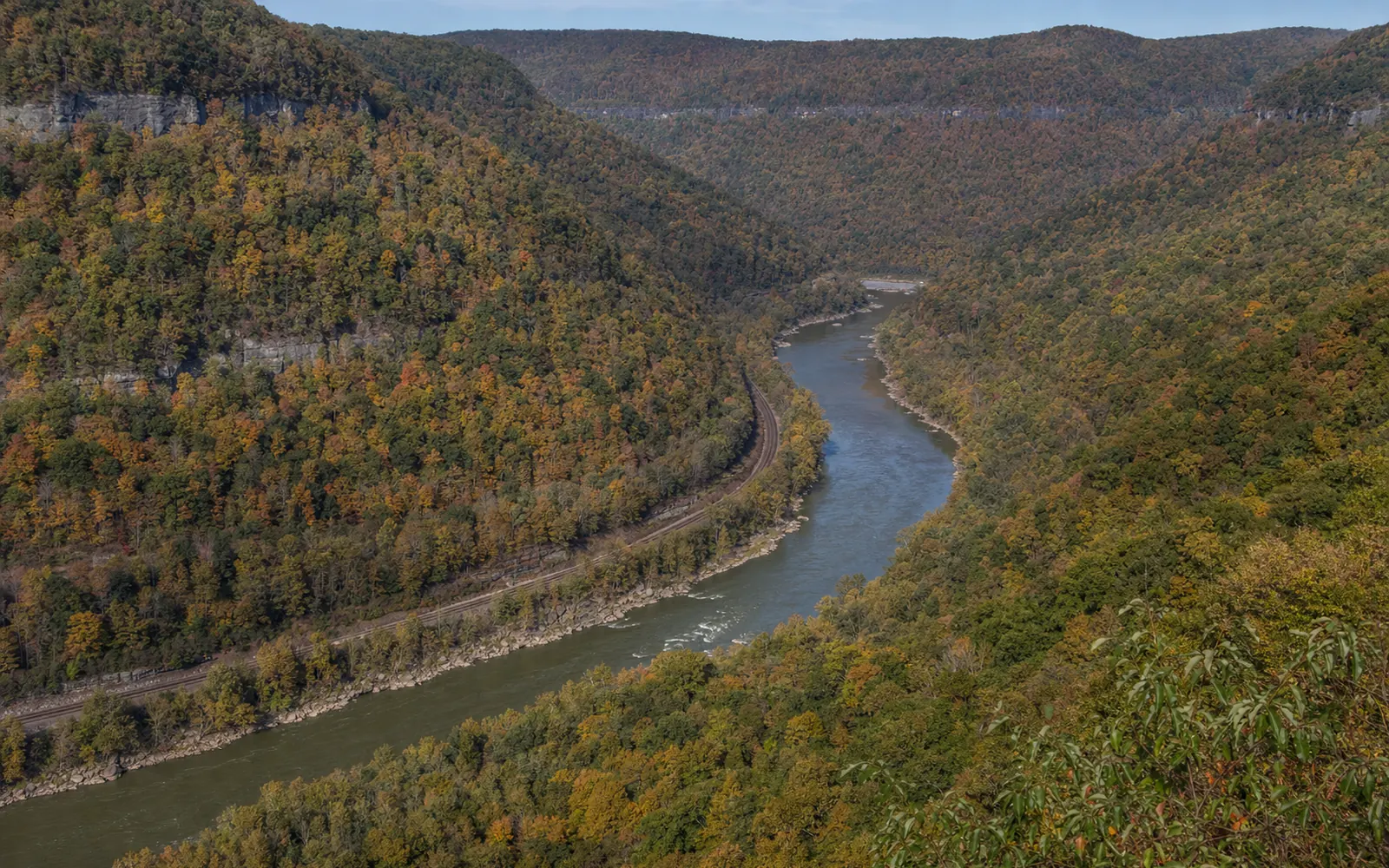 The river and railroad at Quinnimont seen from Grandview, the tracks tracing the river bend deep in the gorge, AI-generated illustration
