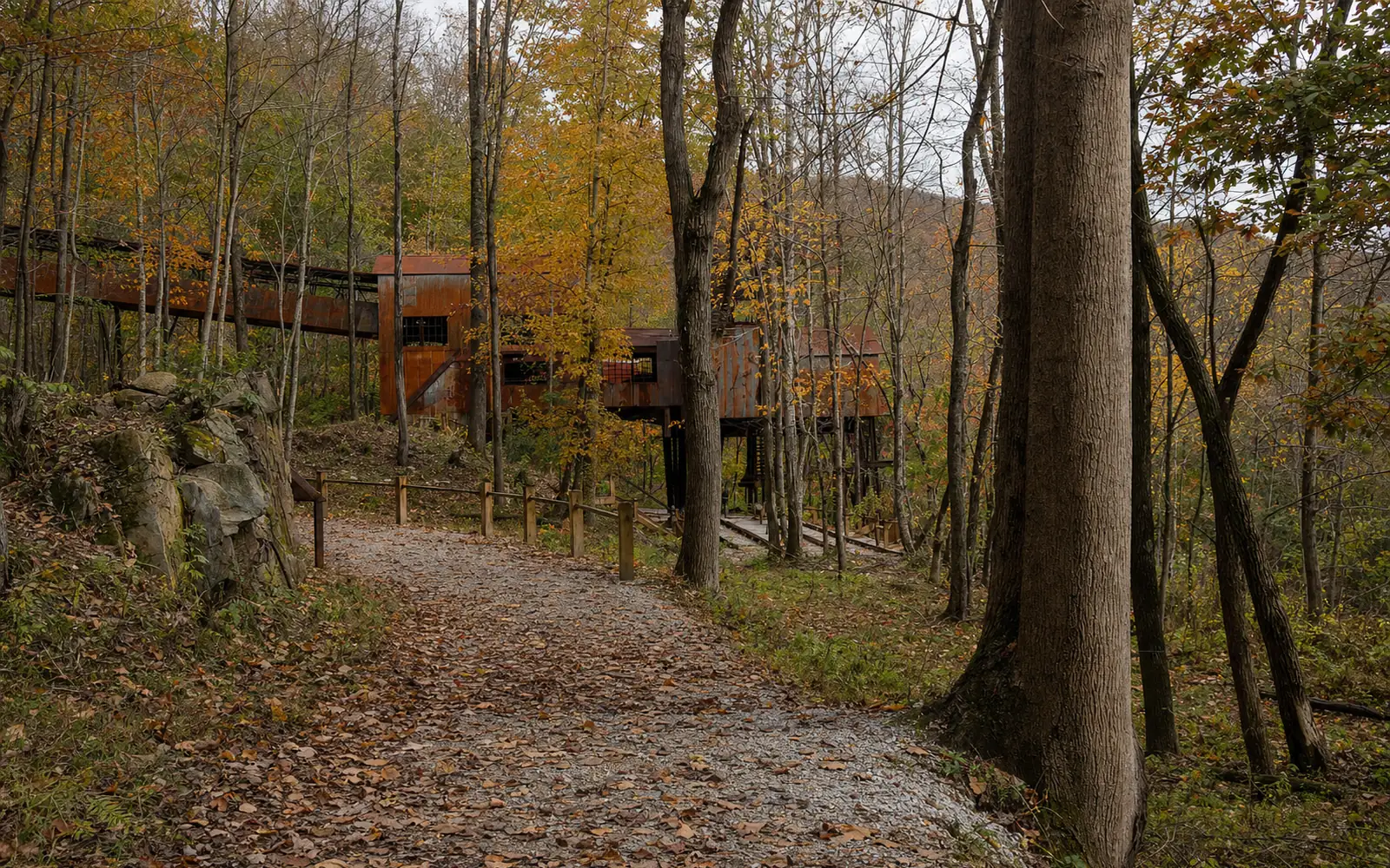 The rusted steel conveyor and wooden-framed tipple at Nuttallburg seen from below, climbing the slope through fall-colored forest, AI-generated illustration