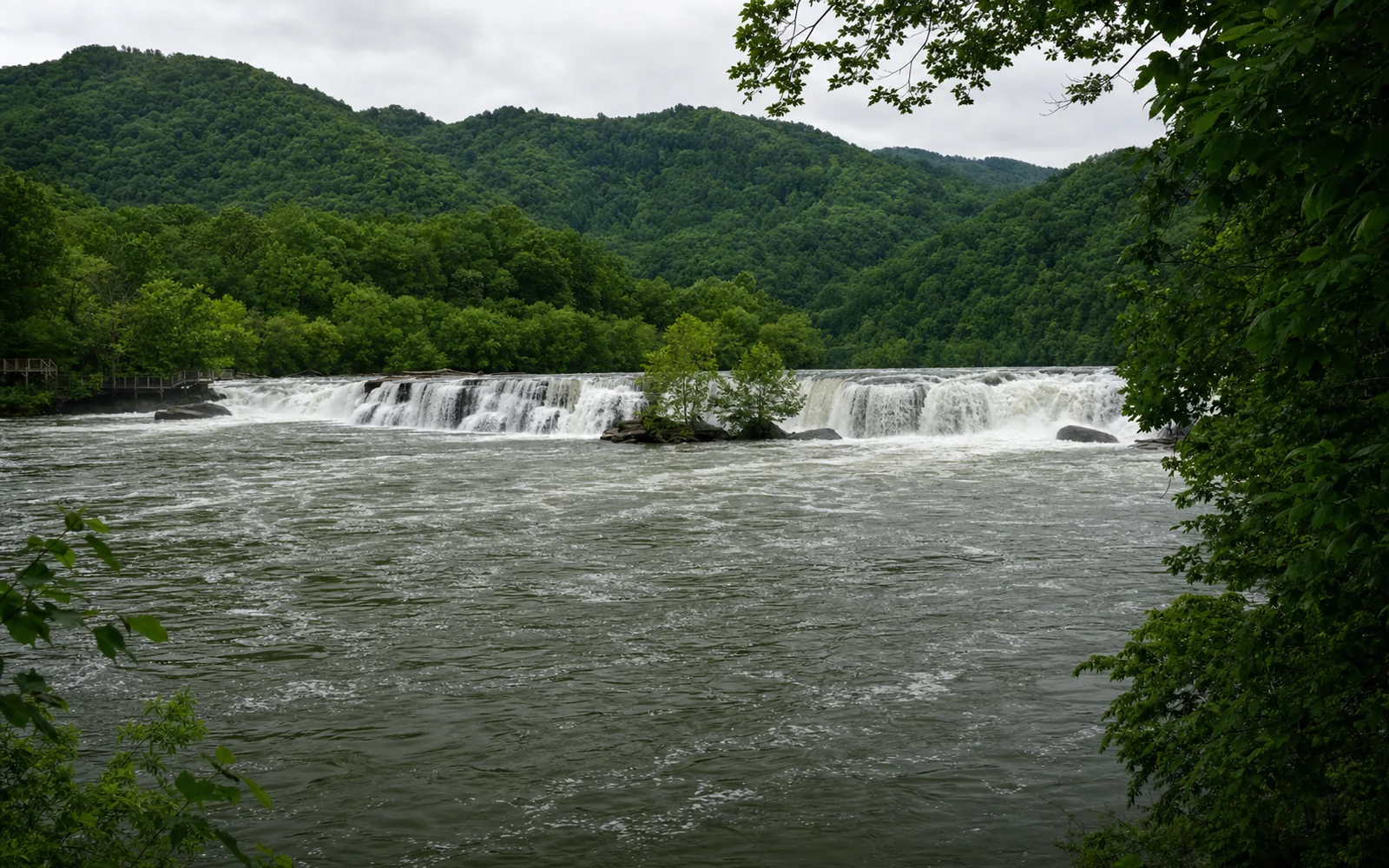 Sandstone Falls stepping across the full width of the New River over sandstone ledges, with wooded islands and the boardwalk at left, AI-generated illustration