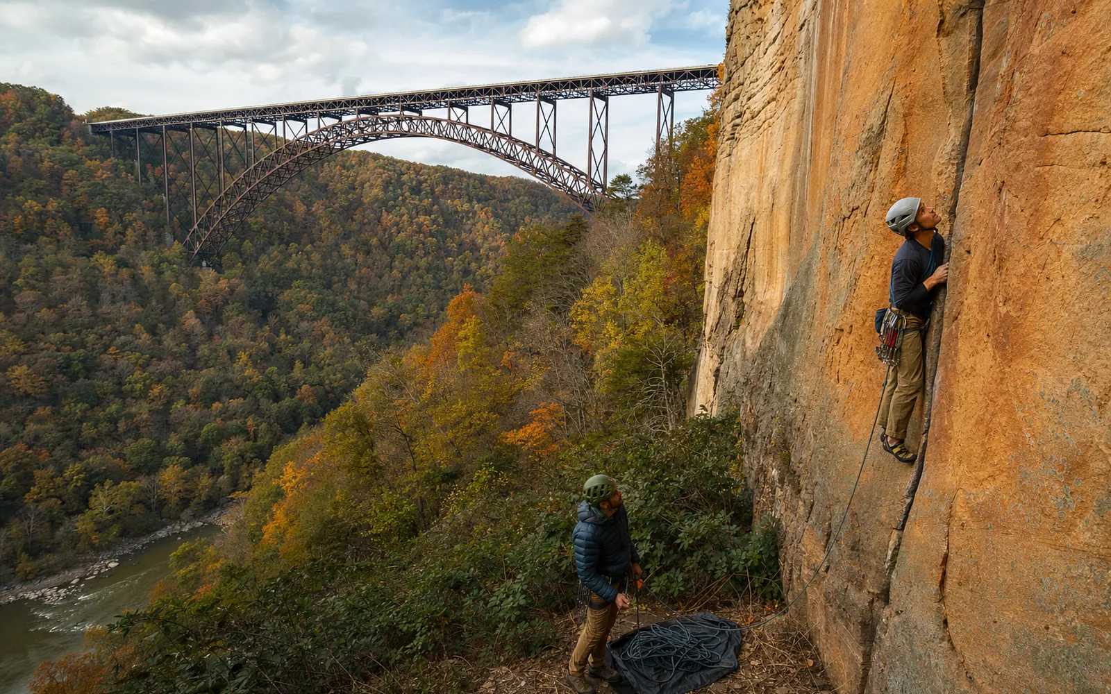 An adult climber leading a vertical crack on orange sandstone at Bridge Buttress, the New River Gorge Bridge's arch visible behind, AI-generated illustration