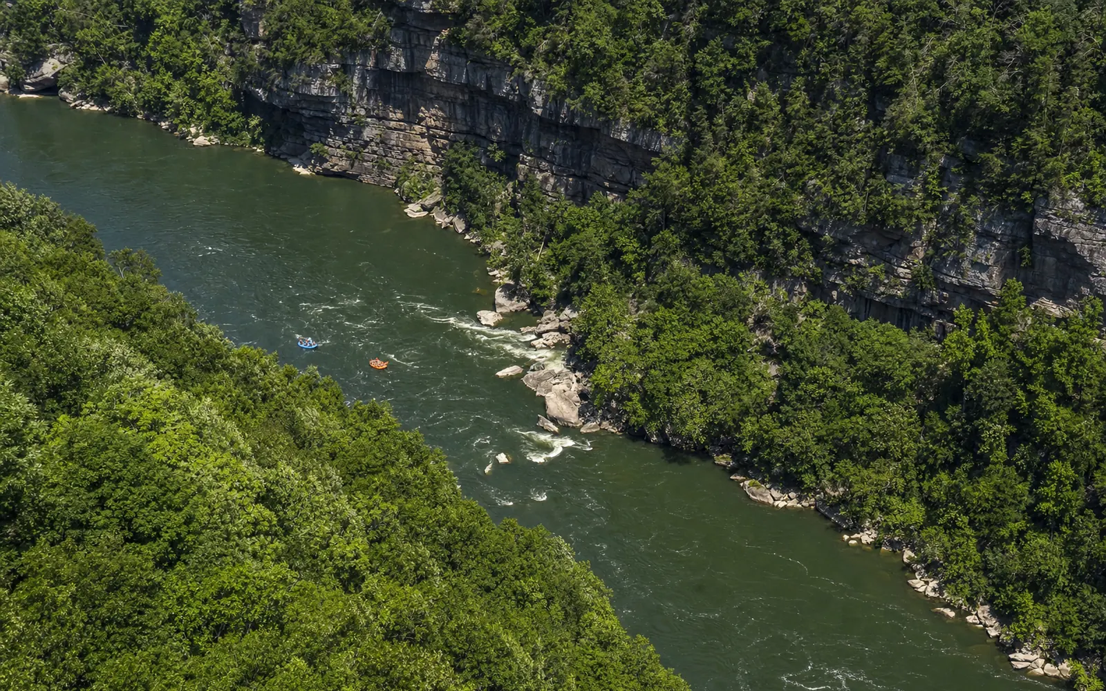 Rafts as small colored specks on the green river nearly 900 feet below Diamond Point, the gorge walls and cliffs framing the bend, AI-generated illustration