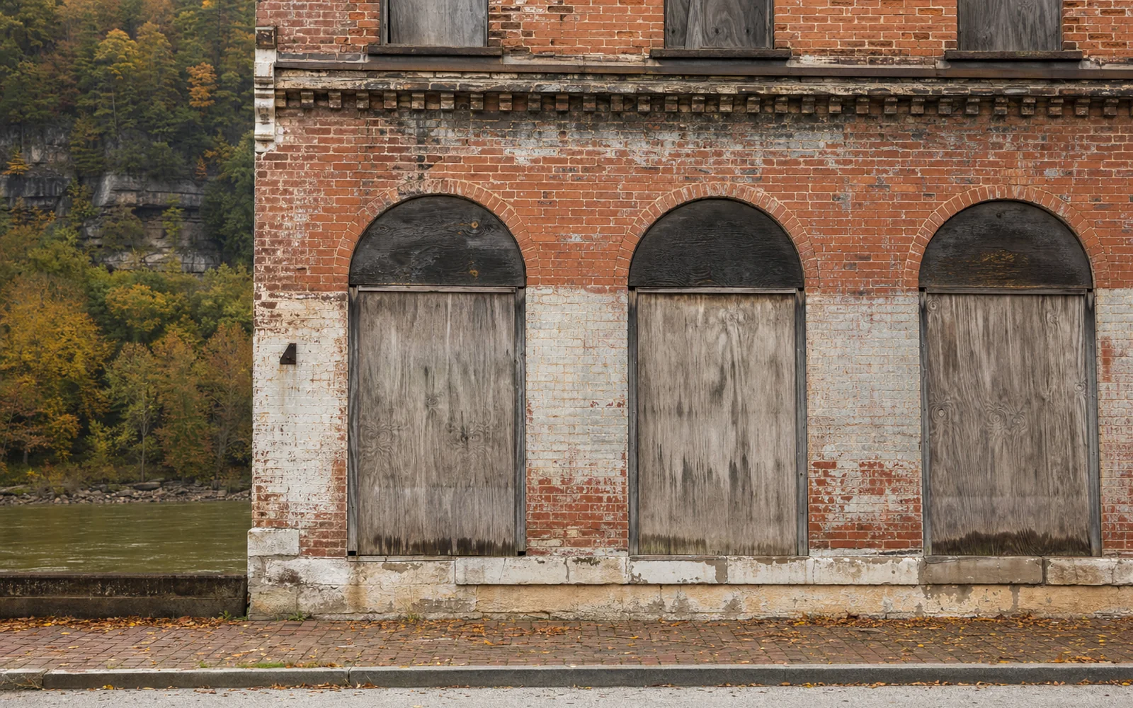 Close view of a weathered brick storefront with boarded arched windows and faded paint, AI-generated illustration