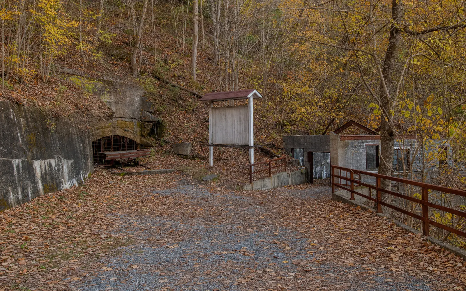 The trail passing through concrete foundations and rusted steel remains of the Kaymoor mine among trees, AI-generated illustration